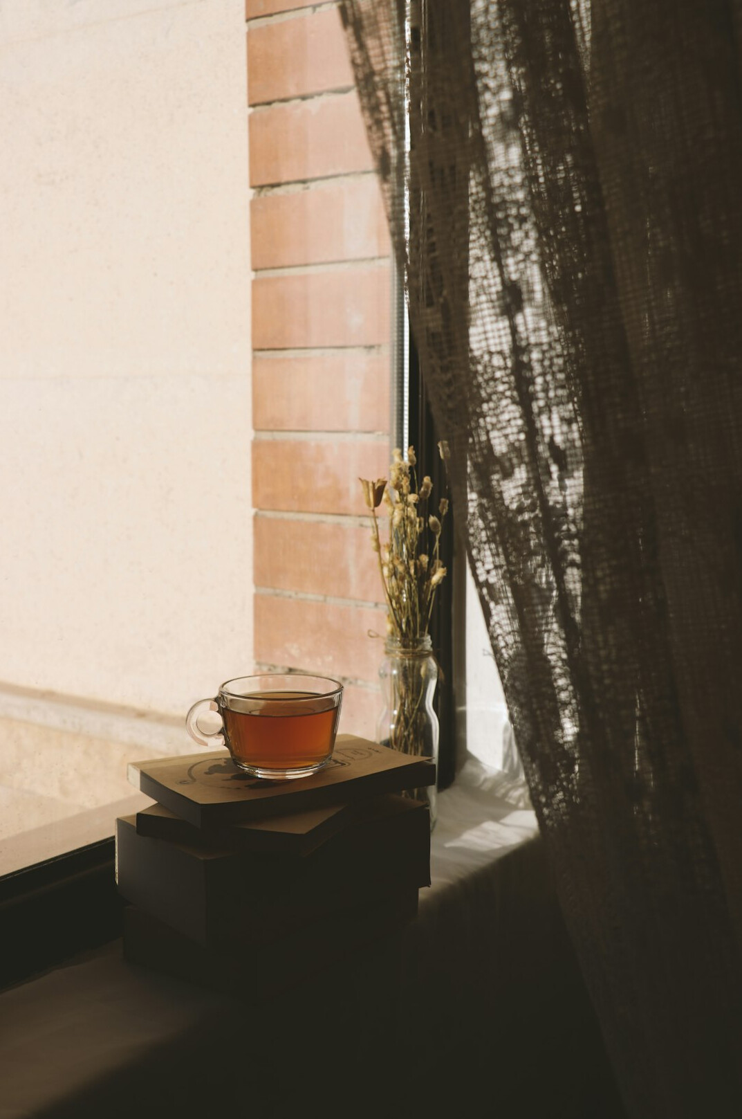 Quiet desk by a window with a notebook, a pen and a cup of tea